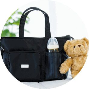 Portable baby bottle and teddy bear in black diaper bag, ideal for parents seeking convenient children's speech and language development solutions.