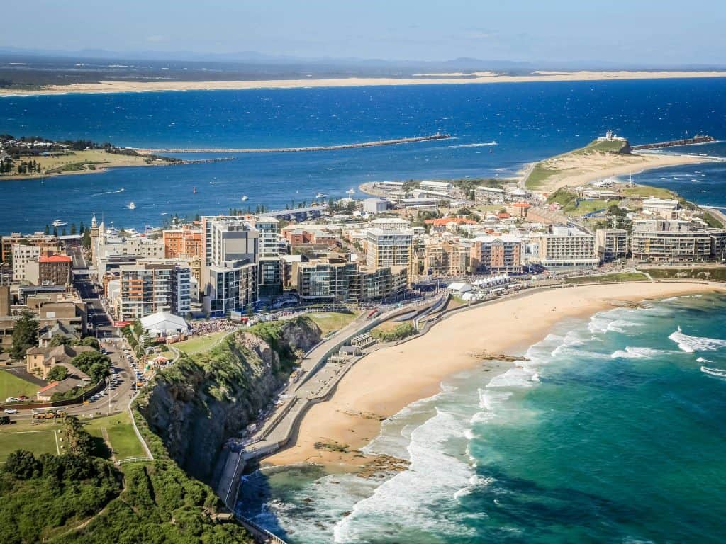Panoramic aerial view of a coastal cityscape with high-rise buildings, sandy beaches, and ocean waters in the background, showcasing scenic beauty and waterfront development.