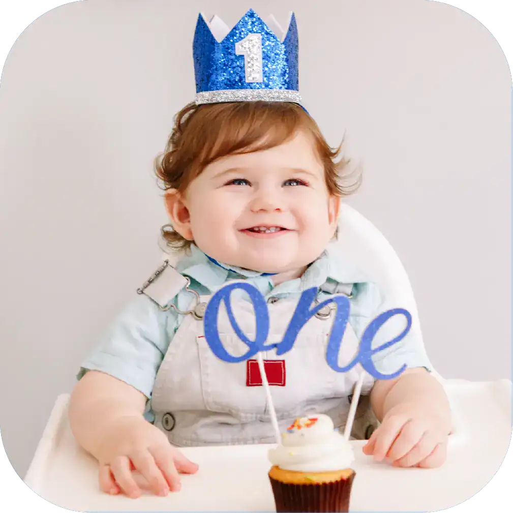 Celebrating a child's first birthday with a cupcake, 'one' themed cake topper, and a joyful smile, highlighting speech therapy and early childhood development.