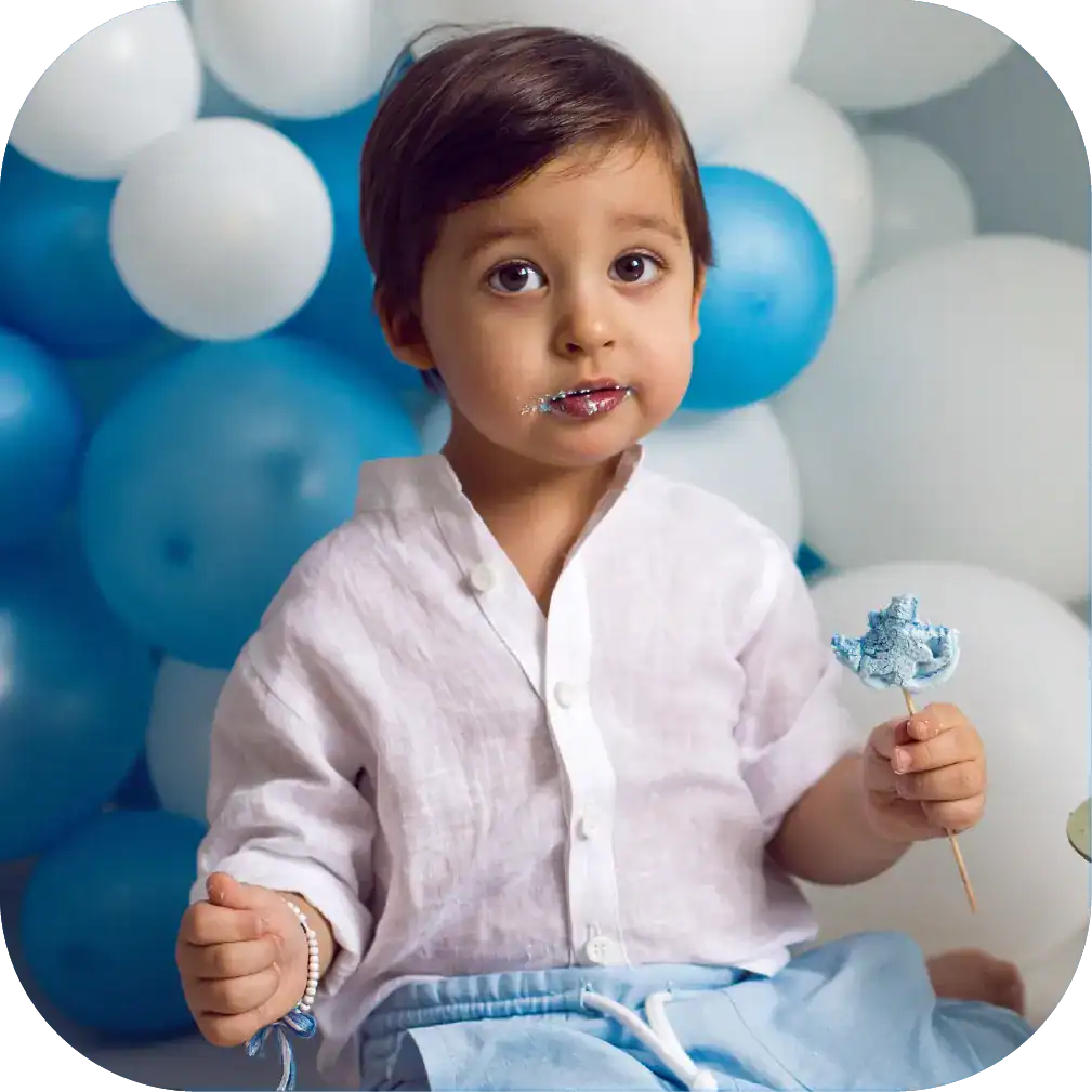 Bright young boy enjoying ice cream at a colourful balloon-themed birthday party, promoting kids' speech therapy and developmental services by Chatterbox Speech.