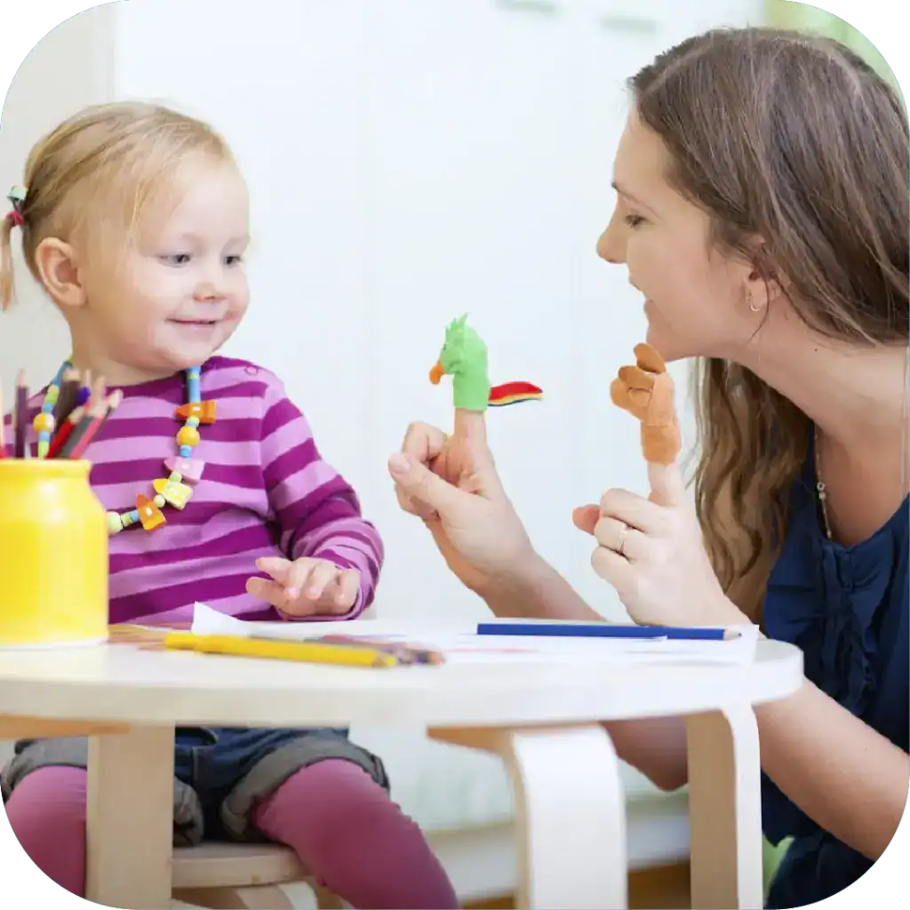 Child speech therapy session with a speech-language pathologist using puppets for children's communication development.