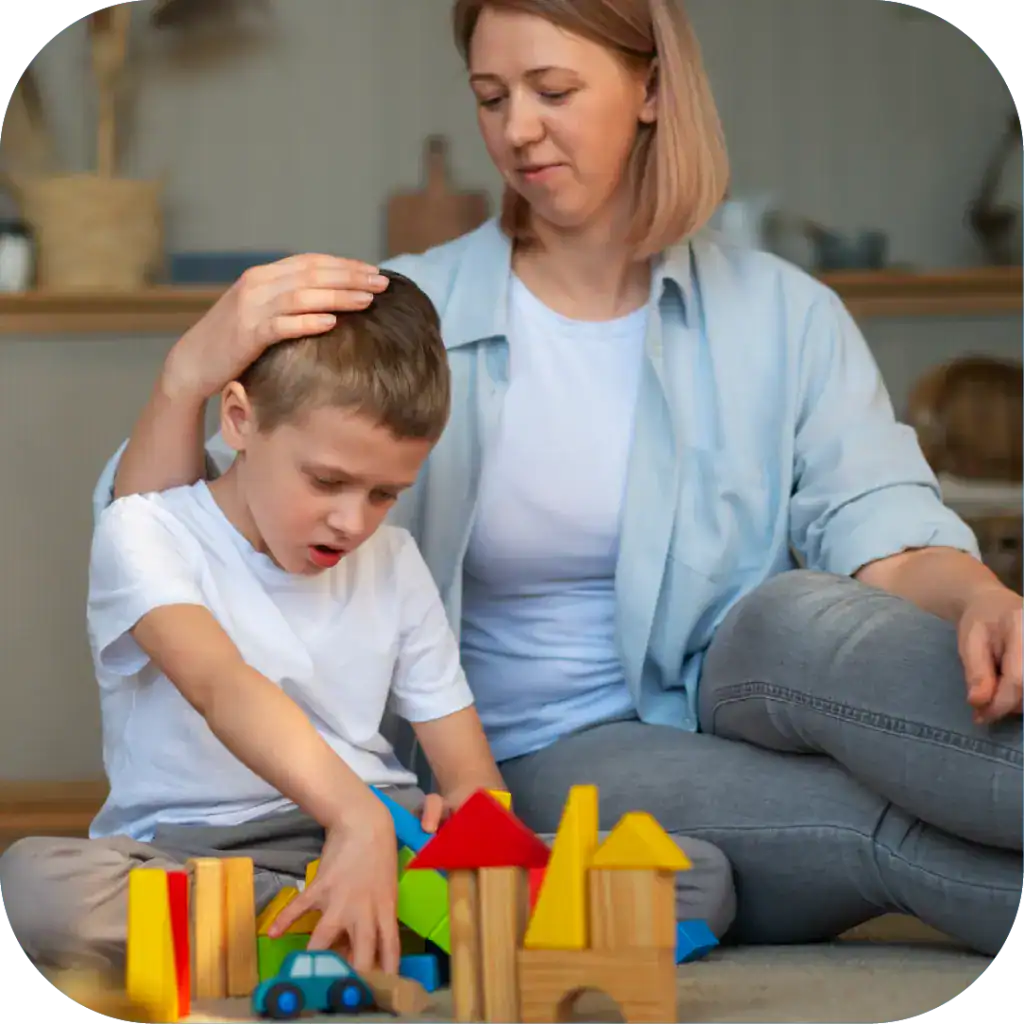 Early childhood speech therapy session with a speech pathologist and young boy playing with colourful building blocks for language development and communication skills.
